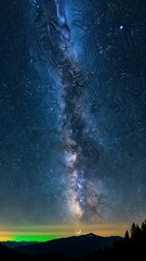 Stunning night sky featuring the galactic center stretching over dark alpine ridges with a faint green aurora glow.
