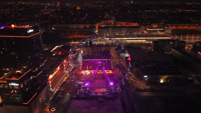 Naechtliches Drohnenvideo ueber Werksviertel in Muenchen, Bayern. Umadum Riesenrad und urbanes Stadtbild nahe Ostbahnhof. Aerial cityscape of Munich at night filmed by drone. Umadum Ferris Wheel
