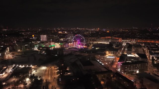 Night drone footage over Munich East showing Werksviertel district and Umadum Ferris Wheel. Aerial panorama of illuminated cityscape near Munich Ost railway station on December 31