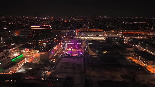 Aerial cityscape of Munich at night filmed by drone. Umadum Ferris Wheel shines in Werksviertel-Mitte near Muenchner Ostbahnhof on New Years Eve, Germany. Luftaufnahme Werksviertel-Mitte in Muenchen