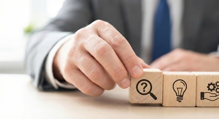 White adult businessman in a suit at the office finds an innovative solution, placing wooden blocks with idea and gear icons next to a question mark