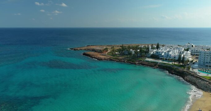 Drone aerial view of Fig Tree Bay coastline with turquoise sea and resort area in Protaras