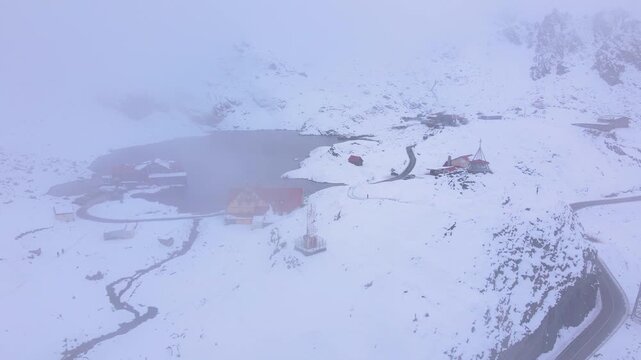 Aerial view at Balea lake in Romania, in winter season. Video was shot from a drone while lowering altitude through the fog with the lake in the view.