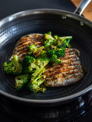 Grilled pork loin steaks and broccoli in frying pan on electric stove