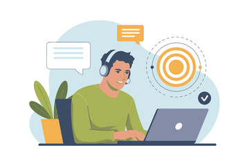 A man wearing a headset sits at a desk with a laptop and plant, engaged in online communication.