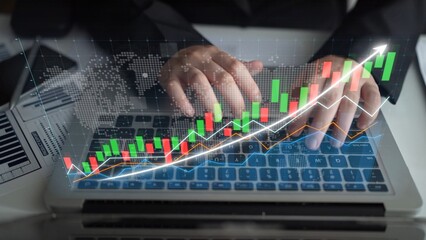 A professional workspace showcasing hands typing on a laptop with dynamic financial graphs and charts overlay that symbolize market trends and investment growth. Copula