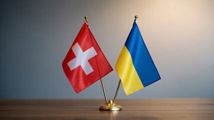 Swiss and Ukrainian flags on gold stands on wooden table