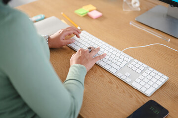A person's hands are typing on a white keyboard at a wooden desk. A smartphone displays the time 11:31.