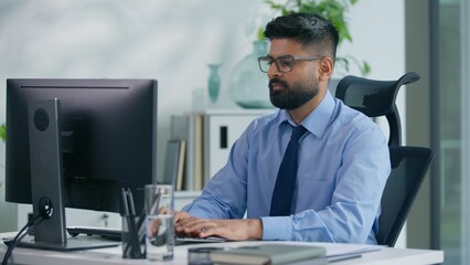 Indian businessman Arabian business man ethnic male worker guy professional entrepreneur working in office typing computer checking documents work process focused busy job online at workplace table