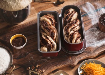 Freshly baked cozonac sits in loaf pans, showcasing its rich, twisted layers filled with nuts and...