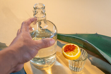 Hand reaching for mezcal bottle with lemon and agave