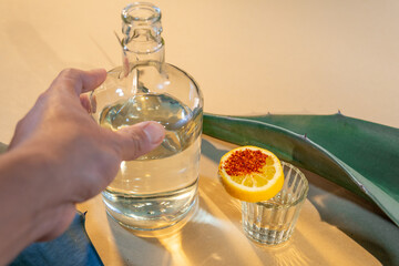 Hand reaching for mezcal bottle with lemon and chili