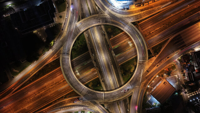 Aerial drone night slow shutter shot of illuminated multilevel ring junction road leaving car light trails