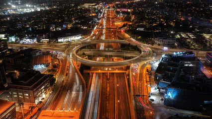 Aerial drone night slow shutter shot of illuminated multilevel ring junction road leaving car light...