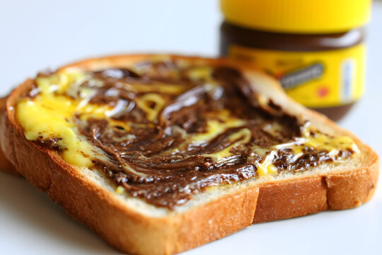 Close-Up Photography of Toasted Bread Slice with Vegemite Spread and Butter on a White Background