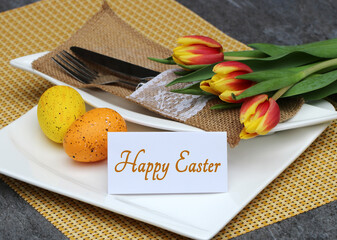 Table decoration with plates, cutlery and Easter decorations; a place card reads "Happy Easter".