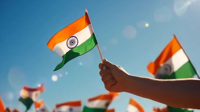 Indian flag held high in hand against blue sky