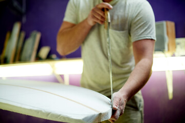 Hands, man and carving surfboard with tools for custom design, shaping guide and repair work. Male person, cutting equipment and board with craft process, diy restoration and manufacturing precision