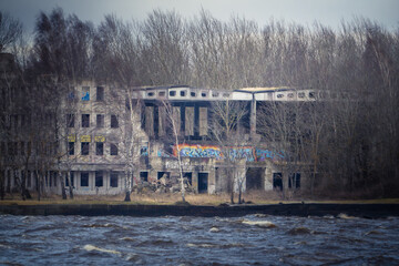 Abandoned brick building with graffiti near a river