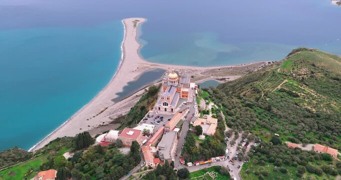 Aerial view of the Sanctuary of Tindari with its golden dome contrasting against the turquoise sea and the sandy beach, Tindari, Sicily, Italy.