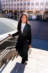 Latina businesswoman smiling walking up city stairs