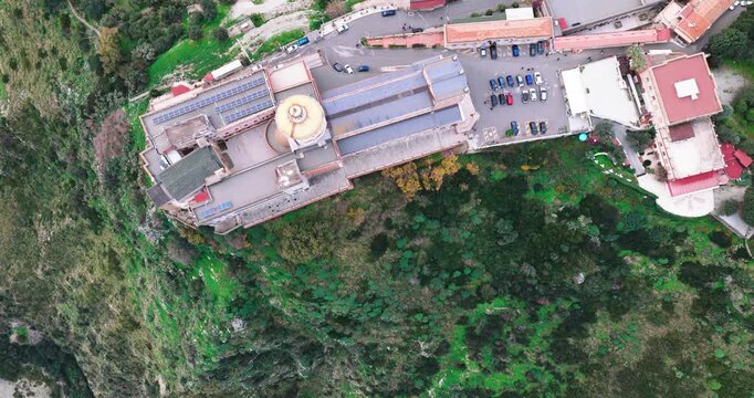 Aerial view of the Sanctuary of Tindari, showing its golden dome and surrounding buildings nestled among the green hills, Tindari, Sicily, Italy.