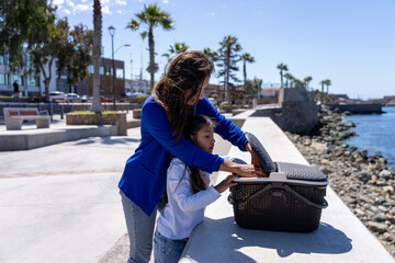 Mother and daughter bonding, preparing for a picnic by the sea on a sunny day