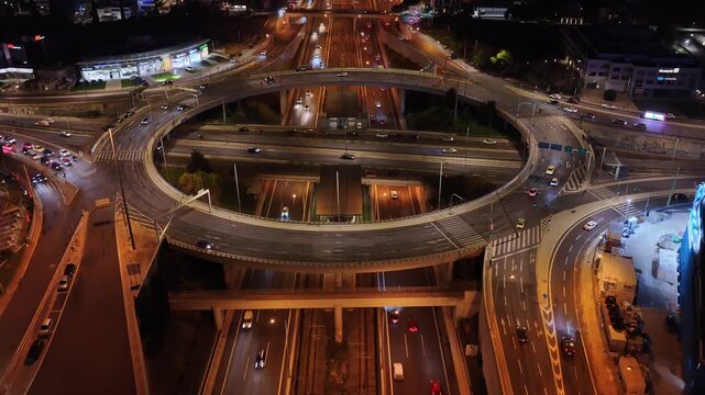 Aerial drone night video of illuminated multilevel ring road junction crossing Attiki Odos and National motorway in Northern Athens, Attica, Greece