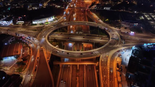 Aerial drone night video of illuminated multilevel ring road junction crossing Attiki Odos and National motorway in Northern Athens, Attica, Greece