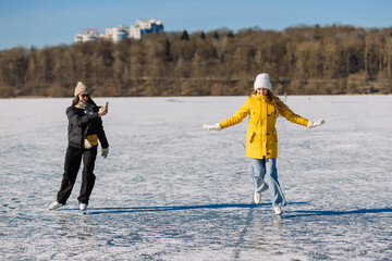 Women ice skating on frozen lake enjoying winter recreation
