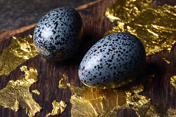 Detailed view of speckled eggs placed on a wooden surface with gold leaf accents showing decorative arrangement