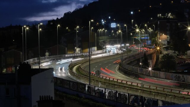 A night-time timelapse capturing the dynamic flow of vehicles and their red and white light trails on a main urban avenue.