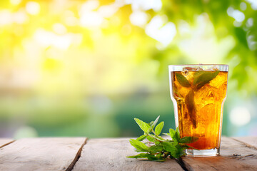 Refreshing iced tea on a wooden table with mint leaves in a garden during sunny afternoon