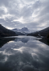 The majestic peak of Txindoki emerges from the winter clouds above the cold waters of the Ibiur reservoir.