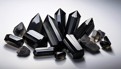 Black Tourmaline Crystals Arranged On A White Surface With Contrasting Light Photo