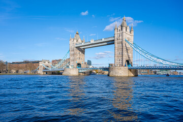 Obraz premium Tower Bridge stands majestically over the River Thames, showcasing its iconic structure against a clear blue sky. Visitors can admire the beauty of London from this historic landmark.