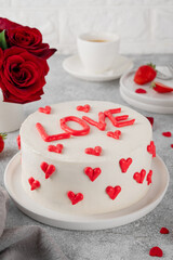 Vanilla strawberry cake with small red hearts for Valentine's day on a white plate on a gray concrete background. Romantic cake.
