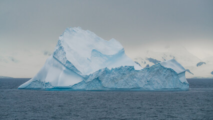 Epic Iceberg Antarctica. Picture Perfect Floating Ice with Snow Covered Mountains in Background. Fine Art Photography. © And They Travel