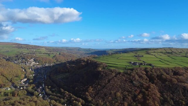high aerial view of the calder valley in autumn showing the town of hebden bridge surrounded by trees and hills with mytholmroyd in the distance