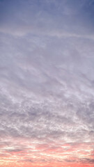 Dramatic sunset sky with textured clouds glowing in pink and orange colors during evening twilight