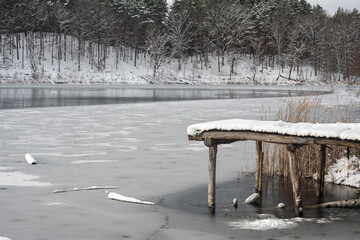 Drewniany pomost przykryty białym śniegiem nad zamarzniętym jeziorem  © qrrr