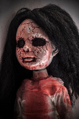 Creepy bloody doll face with long black hair in the dark