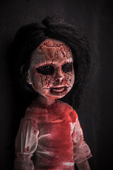 Creepy bloody doll face with long black hair in the dark