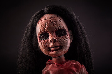 Creepy bloody doll face with long black hair in the dark