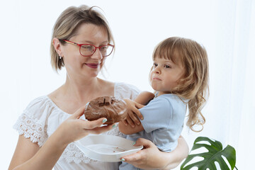A mother giving her child a chocolate-glazed donut, an unhealthy feeding practice 
