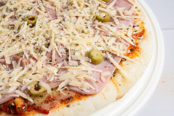 pizza de queso y jamon con aceitunas lista para hornear,