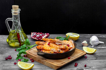 Fried shrimps with lemon, garlic and pomegranate on rustic wooden table
