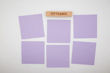 Fototapeta premium September planning concept with wooden block and purple sticky notes on white background. Monthly organization, task management, productivity, workflow and creative planning layout.