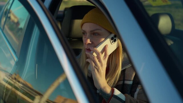 Young blonde woman in car have stressful and emotional conversation on smartphone, look worried and upset while talking and gesturing during difficult phone call