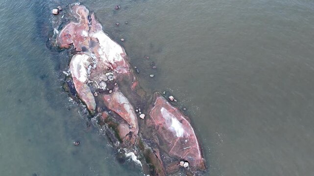Drone footage of a snow-covered rocky islet in cold northern sea